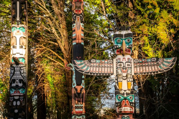 a photo of “Totem Poles” at Brockton Point in winter light, in Stanley Park. The poles represent a number of Indigenous Nations. The poles depict real and mythical events, carved from Western red cedar.