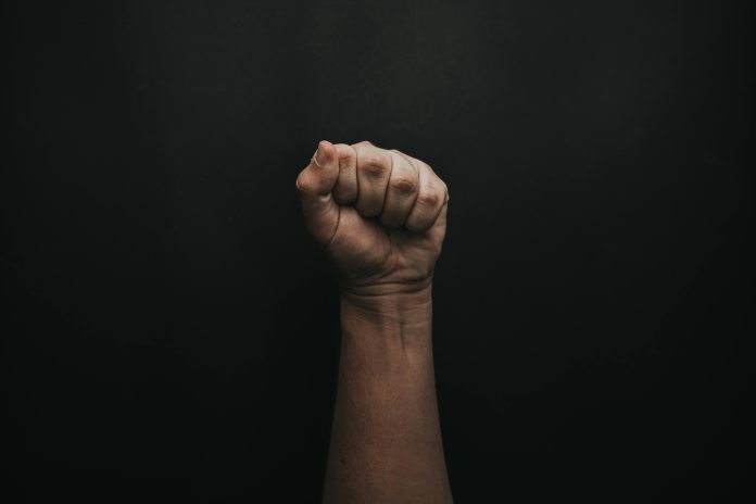 A photo of a fist held upwards against a pitch black background