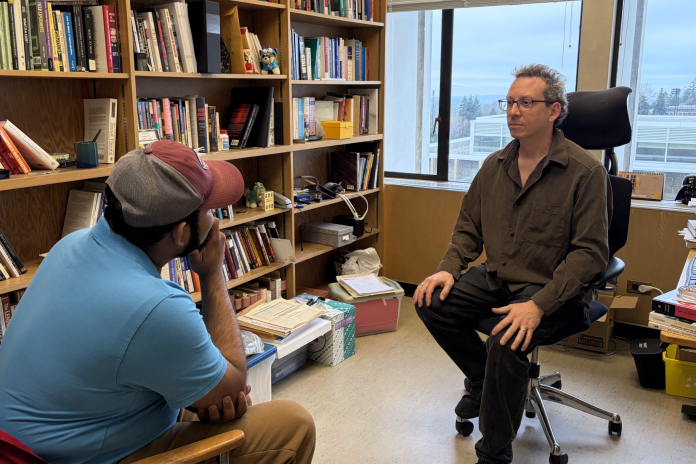 Our Staff Writer poses curiously while interviewing his professor.