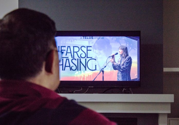 A photo of a person watching the documentary, Hearse Chasing, on the TV