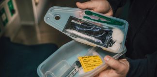 BC’s overdose crisis crosses 10 year mark Image of someone holding a small open portable medical kit containing cotton swabs, tongs, and a catheter, among other items