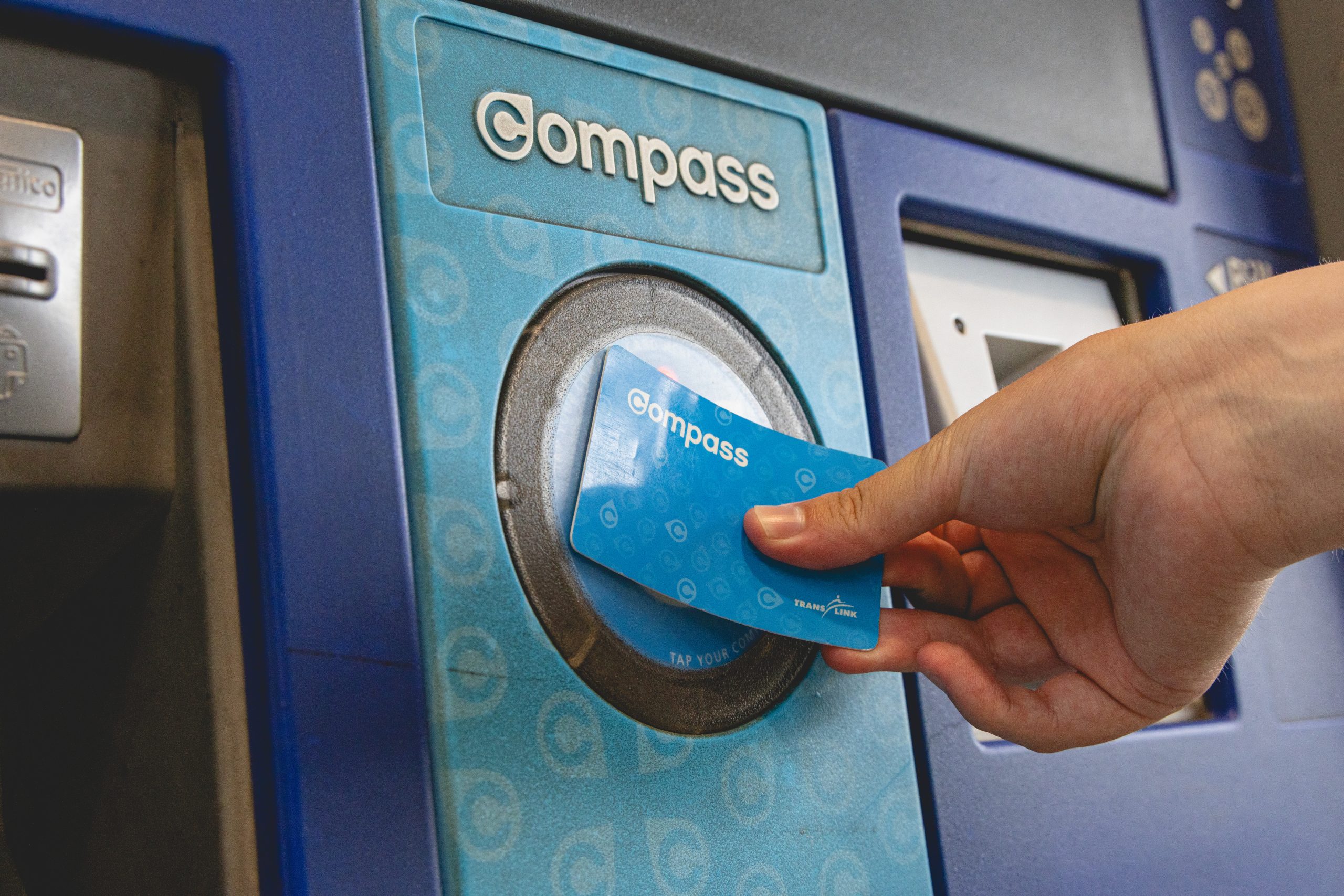 Photo of a person’s hand tapping a compass card at a service machine