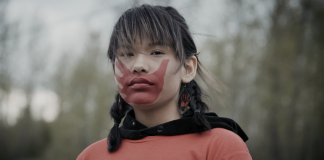 Searching for identity amid ongoing reconciliation A scene from I Am Gitxsan showing a person with a red hand on their mouth