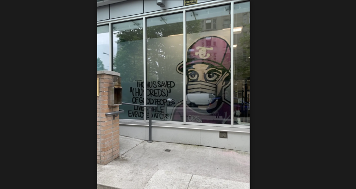 spraypainted art of Thomus Donaghy on the window of an Overdose Prevention Site