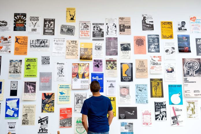A photo of a person looking at posters from Strategies of Assembly