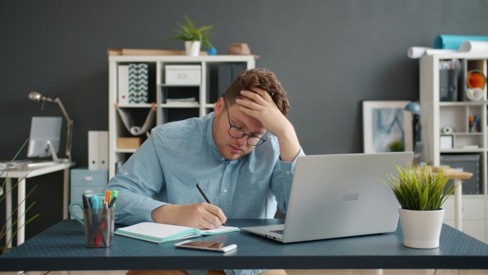 Person sitting at a table looking at medical bills and feeling stressed