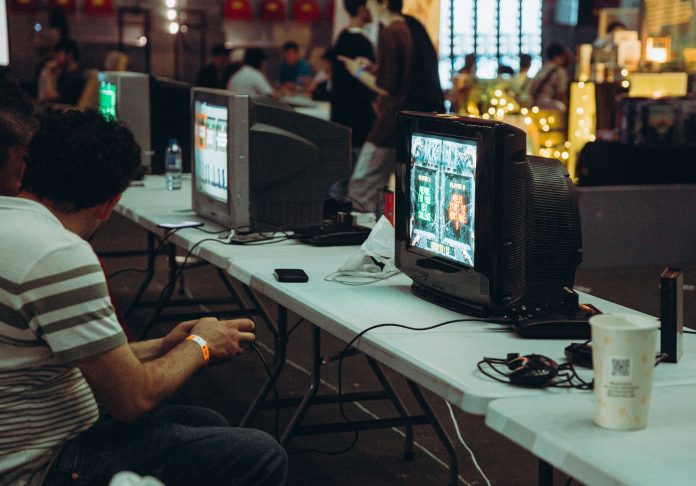 A photo of a man playing video games on a set of computers