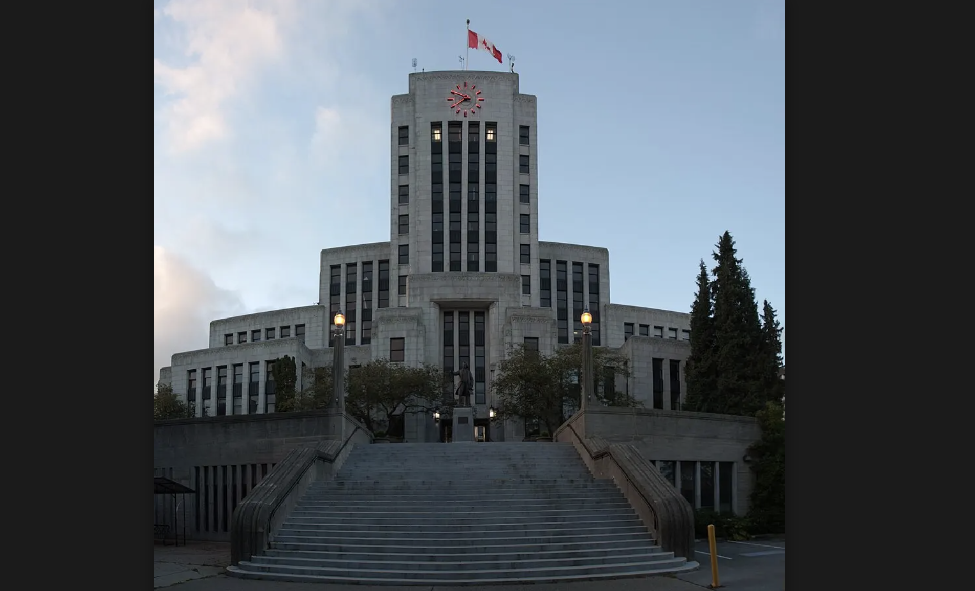 A photo of the exterior of Vancouver City Hall against a bright, blue sky.