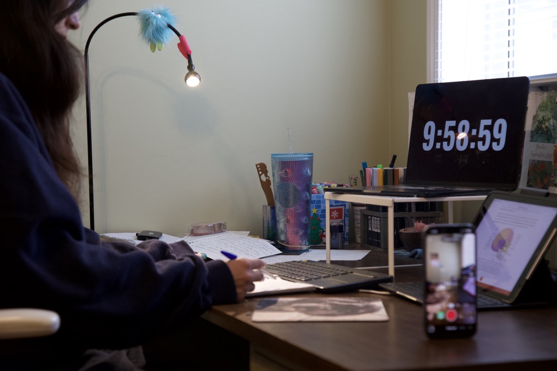 A person films themselves with their phone as they study.