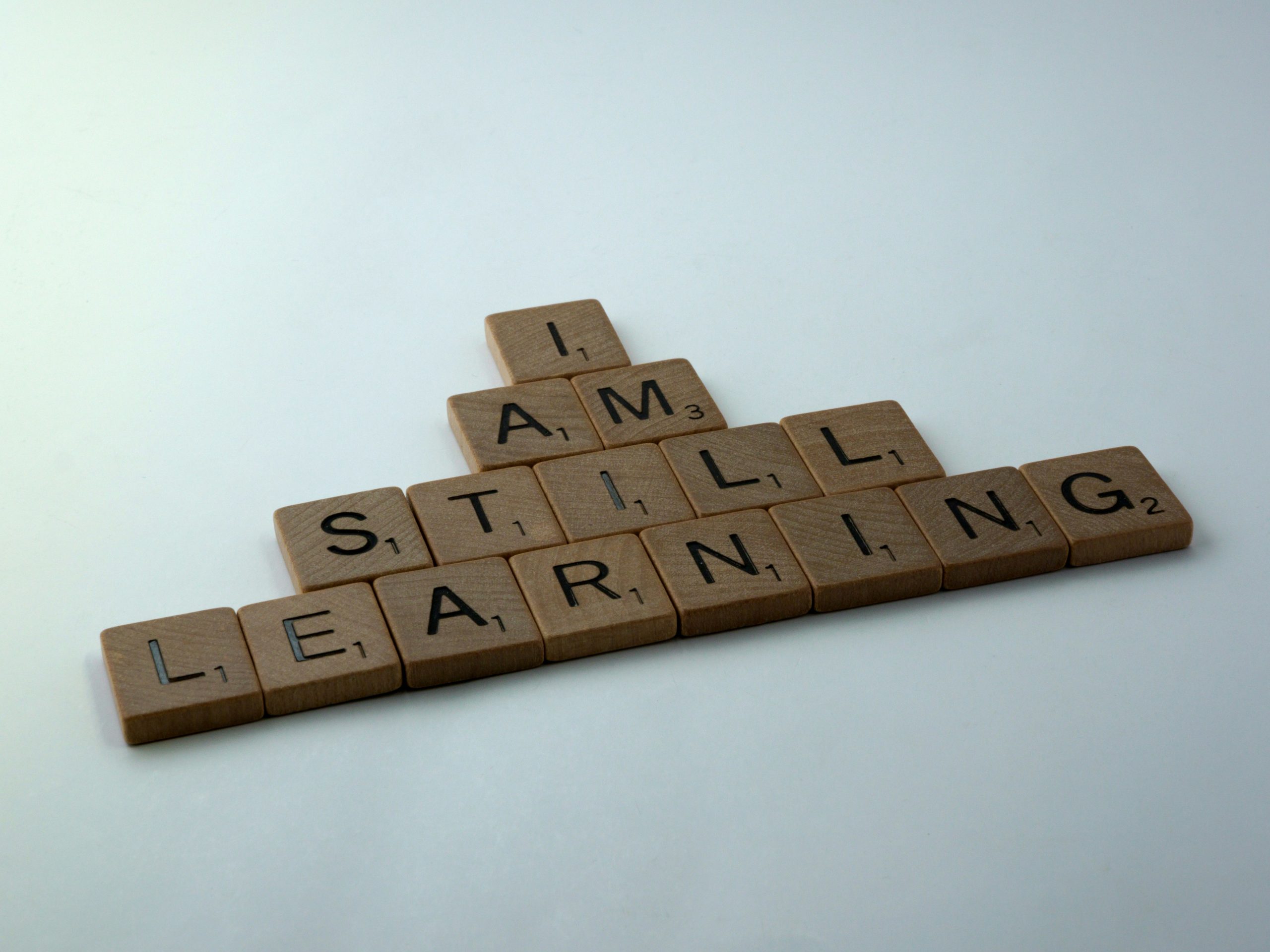 A pyramid of scrabble pieces form the words, “I am still learning.”